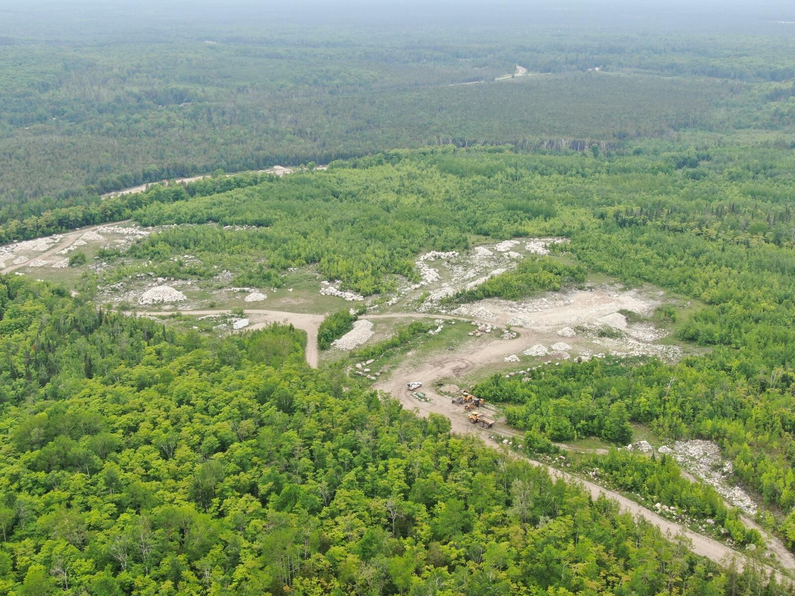 Wide aerial of active quarry operations in forest