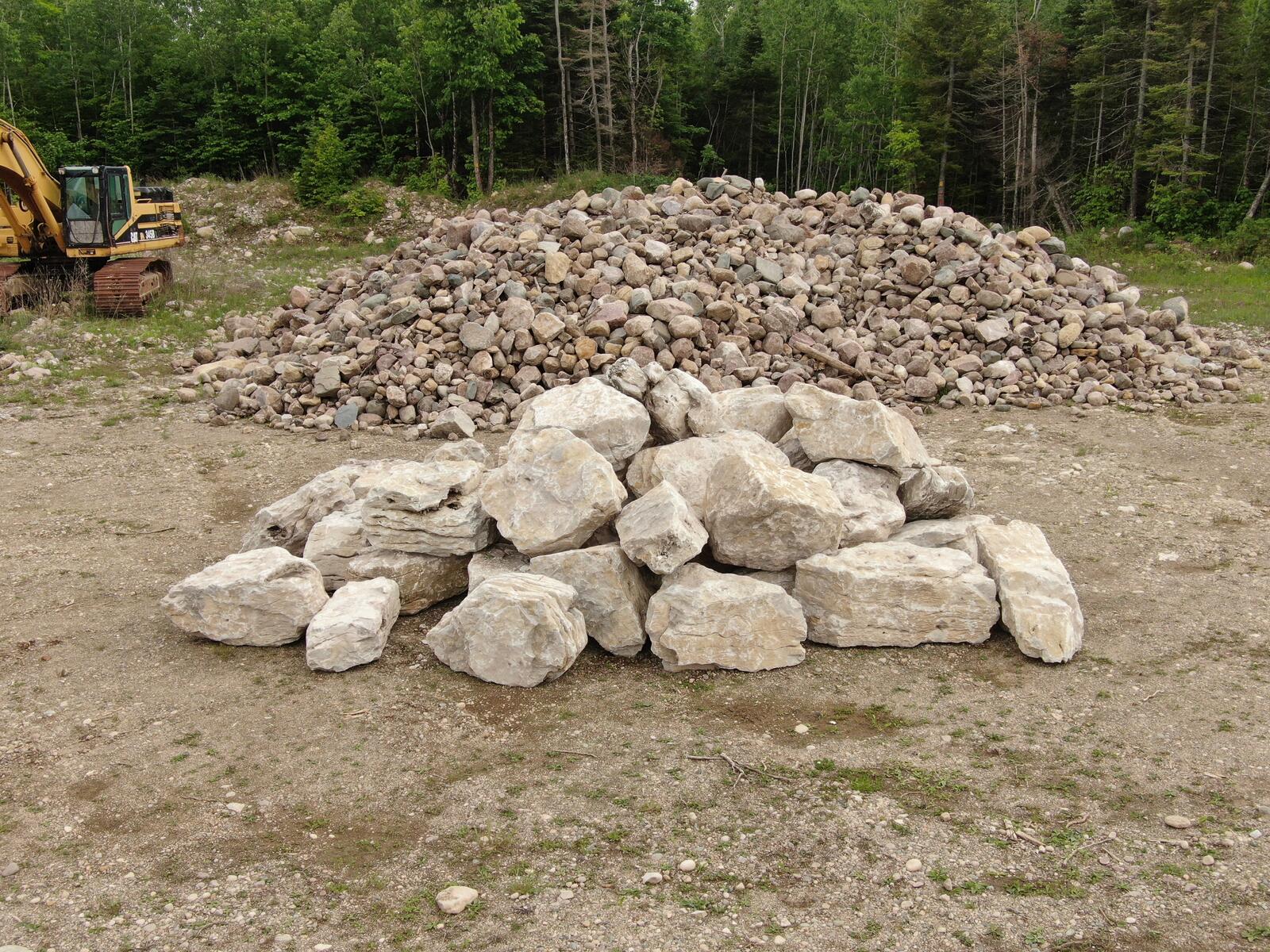 Large pile of mixed landscape stone with excavator nearby